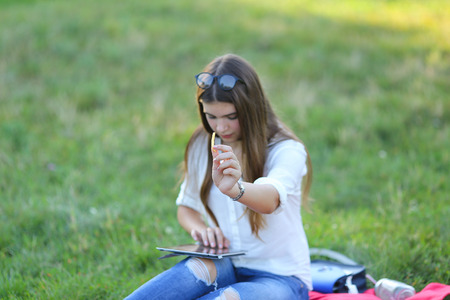 feminine working outdoors with papers in glasses. in the park for a laptop fast food snack and uses a tabletの写真素材