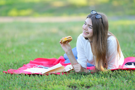 girl lying on the nature and eateth fast food. student working in the park and eat.の写真素材