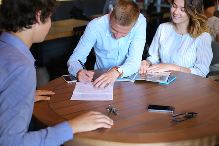 Young business rich couple buy an apartment, property, house, apartment, enter into a contract with a realtor. Signs an agreement with the seller, Leaf catalog pagesの写真素材