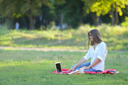 feminine working outdoors with papers in glasses. in the park for a laptop fast food snack.の写真素材