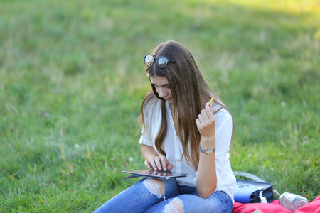 feminine working outdoors with papers in glasses. in the park for a laptop fast food snack and uses a tabletの写真素材
