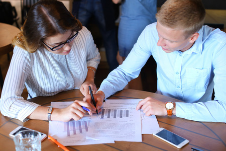 Smart young business men one woman suits sitting on table documents, graphics, technology,  Leaf catalog pages. Team entrepreneurs negotiate, discuss issues, solve problems, agree, talkの写真素材
