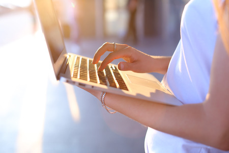 Hand lady press tauchpad keyboard on laptop. Young beautiful female business woman entrepreneur long hair wearing suit standing near center technology sunの写真素材