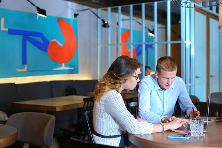 Smart young business men one woman suits sitting on table documents, graphics, technology,  Leaf catalog pages. Team entrepreneurs negotiate, discuss issues, solve problems, agree, talkの写真素材