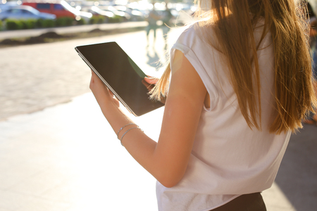 Female work, negotiating, solves problems, browsing touch looking tablet. Young beautiful business woman entrepreneur with long hair wearing suit standing near center technology sun.の写真素材