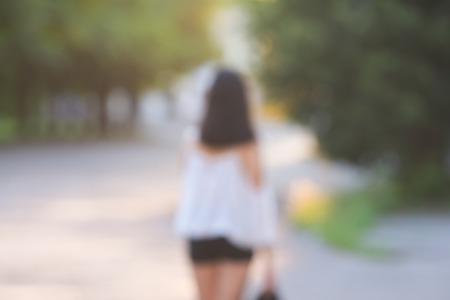 female nature keeps his hat summer sun sunset looks pleased. azitka woman black hair white shirt black shorts out trees around.の写真素材