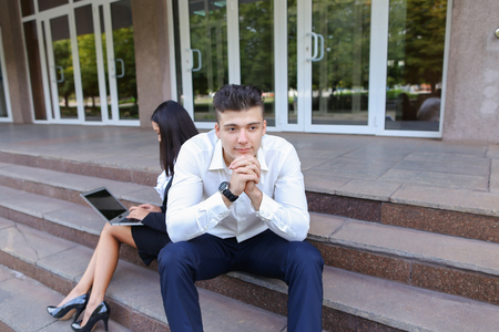 Young contemporary confident people, perspective entrepreneurs, students smiling, chatting with each other, using gadgets, laptops for work with office programs, drawing up business plan, discuss working moments, share of business ideas, solve problems, sの写真素材