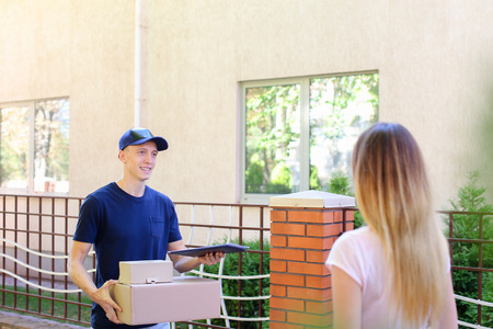 Courier Man Delivered Box to Woman to Home , Ranner Gives Pen and Documents, Girl Signs and Takes Boxes. International Manufacturer of Medical Materials Provides Courier For Purchases, Messenger For You, Courier Man of European Appearance Provides Pen andの写真素材