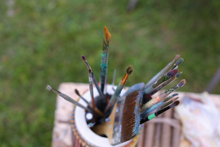 Photo shows thin and thick brush for oil and acrylic paints that in colored pencils and stands with other artistic objects that lie on gray table in park in open air. Concept of art materials store advertising art tools and paints, hobby and interests.の写真素材