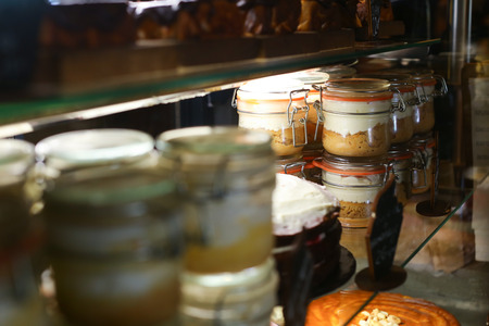 On glass racks stand cakes and glass jars in which poured mousse, pudding in candy store, cafes.Concept of bakery products, delicious food, pleasure, confectionery, restaurant business.の写真素材