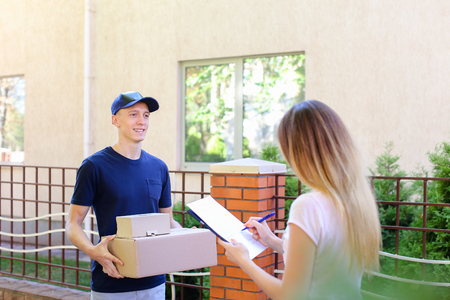 Courier Man Delivered Box to Woman to Home , Ranner Gives Pen and Documents, Girl Signs and Takes Boxes. International Manufacturer of Medical Materials Provides Courier For Purchases, Messenger For You, Courier Man of European Appearance Provides Pen andの写真素材