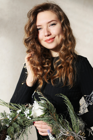 Close portrait of girl with beautiful smile with dimples and curls on blond hair. Woman holds wreath or floral arrangement. Concept of happiness, carefree, beauty, and shampoo ads, solar fun-filled day.の写真素材