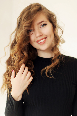 Close girl portrait with beautiful smile with dimples and curls on blond hair. Concept of happiness, carelessness, beauty and advertising shampoo.の写真素材