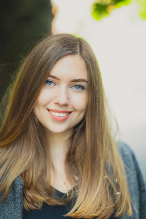 Close portrait of girl with a dimples smile and looking at the camera with long blonde hair. Woman lit with happiness, health and beauty. Concept of happy beauty life and  greetings.の写真素材