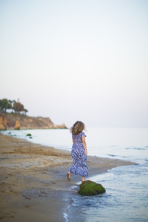 Young woman came to rest to sea coast. Girl run smile dressed in long dress, European appearance. Concept female beauty, enjoy life in travel and tourism in the town.の写真素材