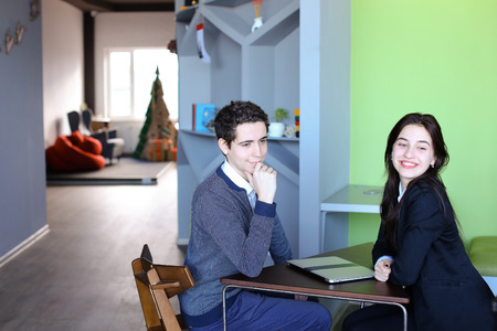 Two attractive people, guy and girl are looking at camera and posing, smiling with broad smile,...