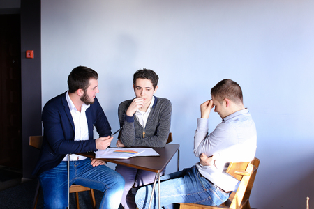 Three young men who are held discuss important questions about work and general business. Guy with...