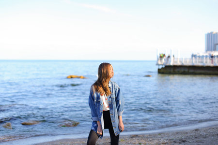 Beautiful girl came to sea to enjoy sunset and feel aroma of fresh salt water.の写真素材