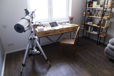 Internal conditions and arrangement of working area and office in bright and spacious room. In room there wooden simple table with metal black supports on which there laptop and notebooks and diaries, wooden chair with soft upholstery, large minimalist boのeditorial素材