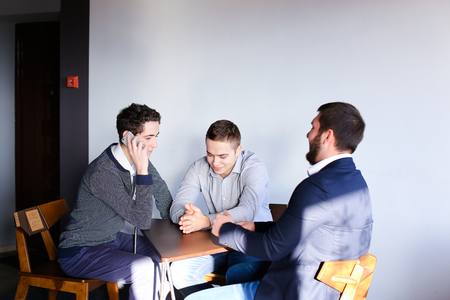 Successful male IT-experts conduct conversation and with help of gadget come up with new ideas for development of applications and programsの写真素材