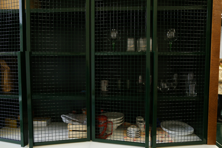 Cabinet wooden with green shelves and green inside with grid doors and shelves, for storing food of companys workers and dishes that stands on table in office in recreation area. Concept of place for work or office space, office environment and comfort coのeditorial素材