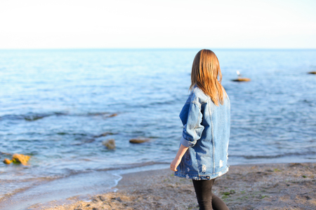 Beautiful girl came to sea to enjoy sunset and feel aroma of fresh salt water.の写真素材