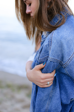 Shooting close-up portrait of wonderful young woman who stares into distance at sea wavesの写真素材