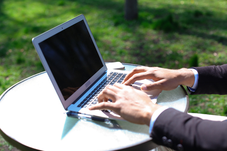 Guy sits by table near phone and using laptop, clicking keyboard.の写真素材