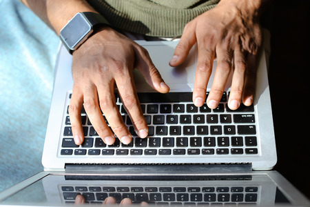 PR manager using keyboard on laptop.  man has long fingers and neat nails. Concept of modern...