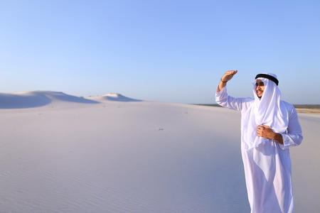 Confident Muslim guy with serious face puts hand to chin and reflects on future plansの写真素材