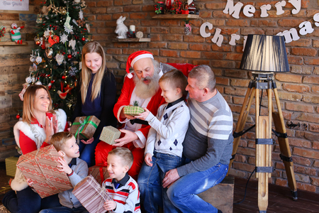 Friendly family and Santa Claus show that everything good in cozy spacious room decorated for New Years holidays with beautiful floor lampの写真素材