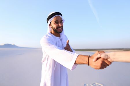 Swarthy, handsome Muslim with short dark hair dressed in kandura, long, spacious dress made of white unpainted cotton with knitted lace cap of hafia shake handsの写真素材