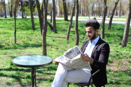 Man sits on chair near table and reading newspaper.の写真素材