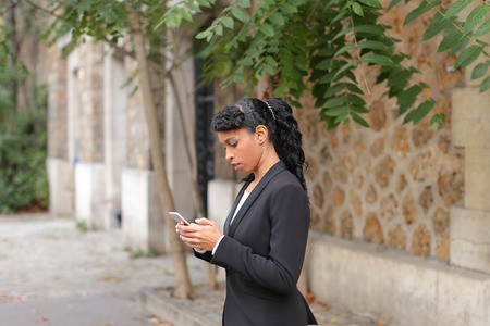 Young girl writing message to boyfriend by smartphone in the park.の写真素材