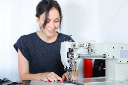 seamstress discuss work with boss using mobile, young pretty woman with ponytail sitting near table...