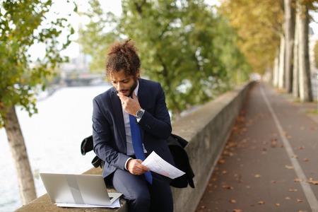 Young actor learning by heart new role for performance in Paris theatre with laptop near Eiffel Tower. Handsome man dressed in suit reading and gesticulating. Concept of preparing for speech on big scene.の写真素材