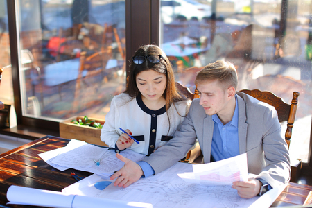 Young female student talking with architecture professor about course project. Pretty girl dressed in blouse speaking with man in grey suit. Concept of educational consulting at catering establishment.の写真素材