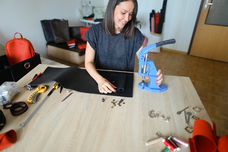 Sales manager working in firm dealing with leather products making list of produced bags, wallets...