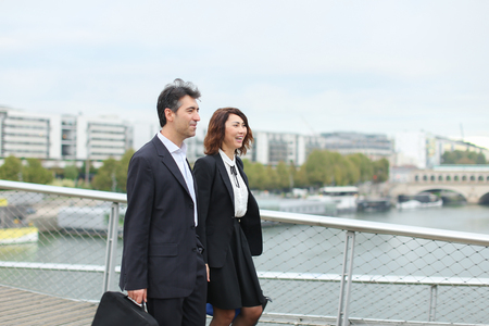 economists walk during lunch break, married American middle-aged couple going to have snack. Man and woman smiling communicating wearing strict suits. Concept of business clothes or fashionable man and woman outfits.の写真素材
