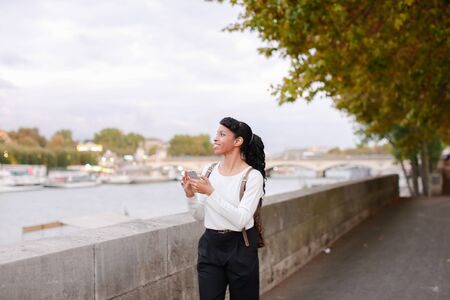 Model came to Paris for work. Lady walking on street near Eiffel Tower and making videos of sights using smartphone in breaks between photoshoot.の写真素材