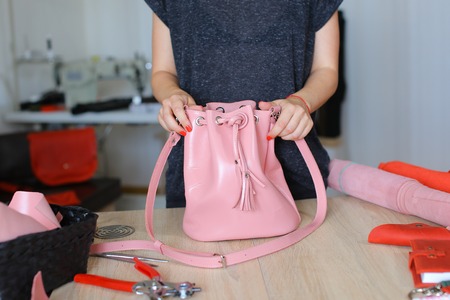 Seamstress took part in competition and won pink leather backpack and purse. Happy young woman...