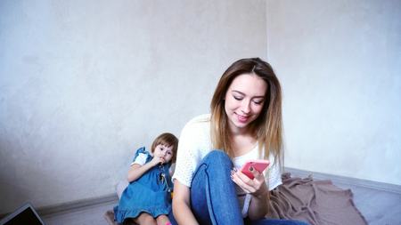 Portrait of happy girl and young mother who talking on smartphone and smilingの写真素材