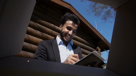 Boy pins into box and write with pen on papers. Man has black beard and short hair. Muslin dressed...