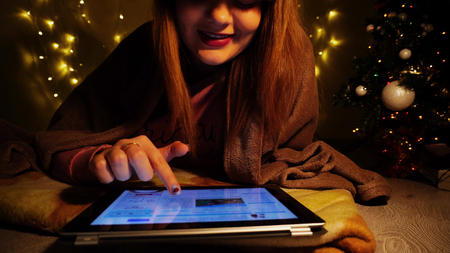 Pretty teenager preparing for New Year speech on tablet. Nice female person reading news. Concept of learning poetries by heart and reading information using Internet.の写真素材