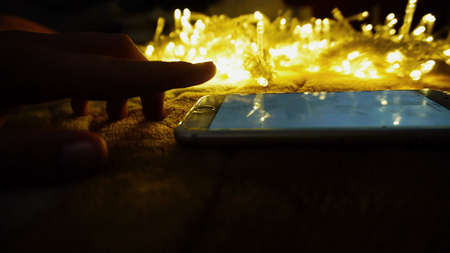 Amazing gadget with sparkling garlands on background. Yellow LED lamps on cord. Concept of...