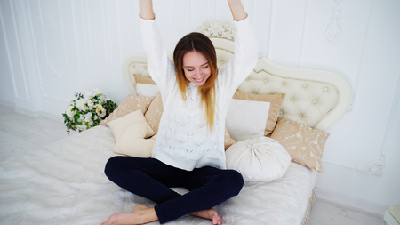 Charming Lady in High Spirits Have Fun and Dancing While Sitting on Large and Beautiful Bedding.の写真素材