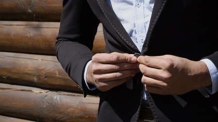Man stands by wooden building and talking by phone, wears sunglasses. Guy has beard, short hair and...
