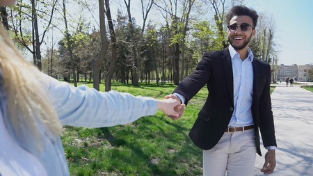Young girl following brother holds hand. Man has short dark hair, beard, dimples on cheeks and wears black jacket and blue shirt. Concept of good program for out-of-town students and university programs.の写真素材