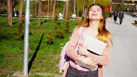 Jocund American tourist with close up thumbs up smiling and looking at camera. Concept of visiting Europe and energetic youth. Young girl wears casual clothes and backpack.の写真素材