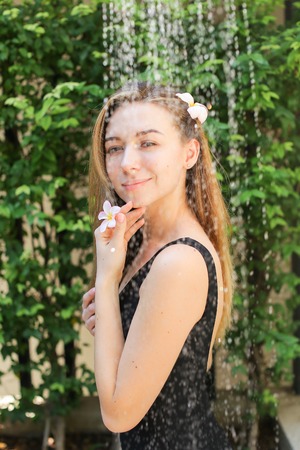 Soft sunny portrait of girl who gets pleasure from soul, Drops of water fall on female. concept of hygiene, taking care of themselves on trip, warm countries.の写真素材